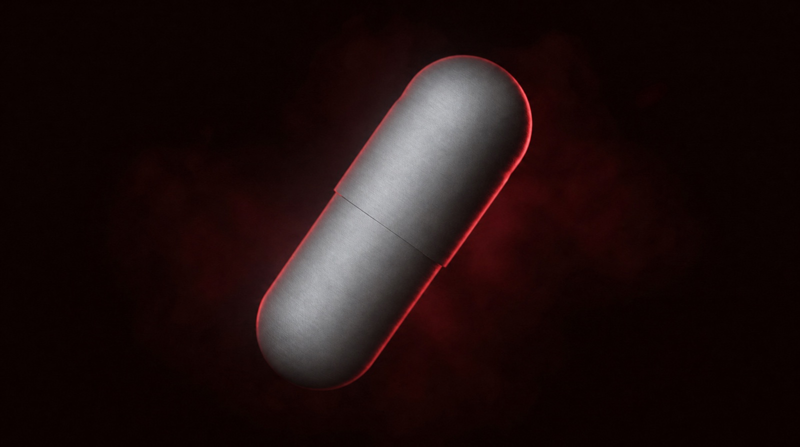 A single polished silver Pump'd capsule lit by a deep red rim light against black
